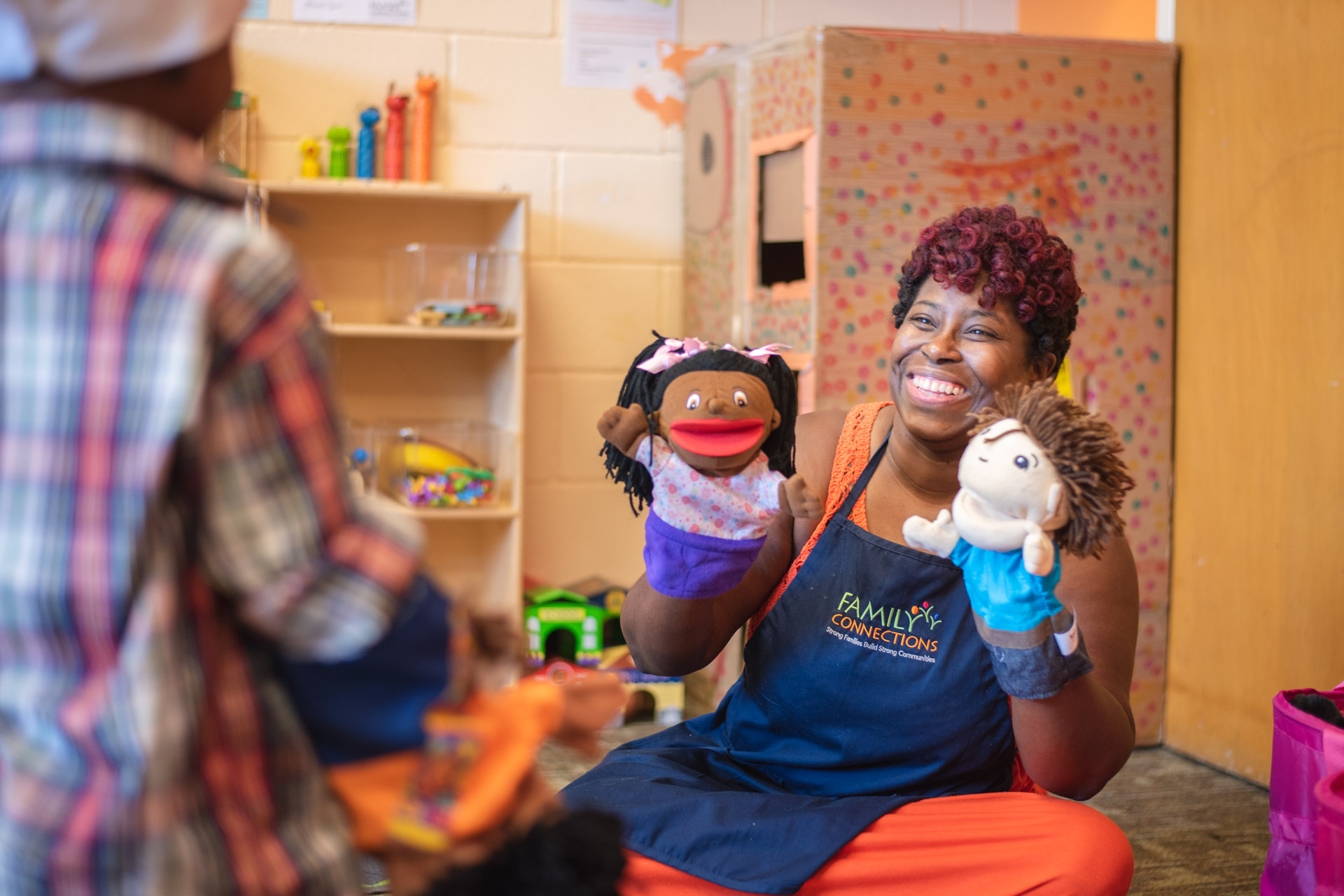 Keesha Tolliver holding a brown skinned puppet and a light skinned puppet.