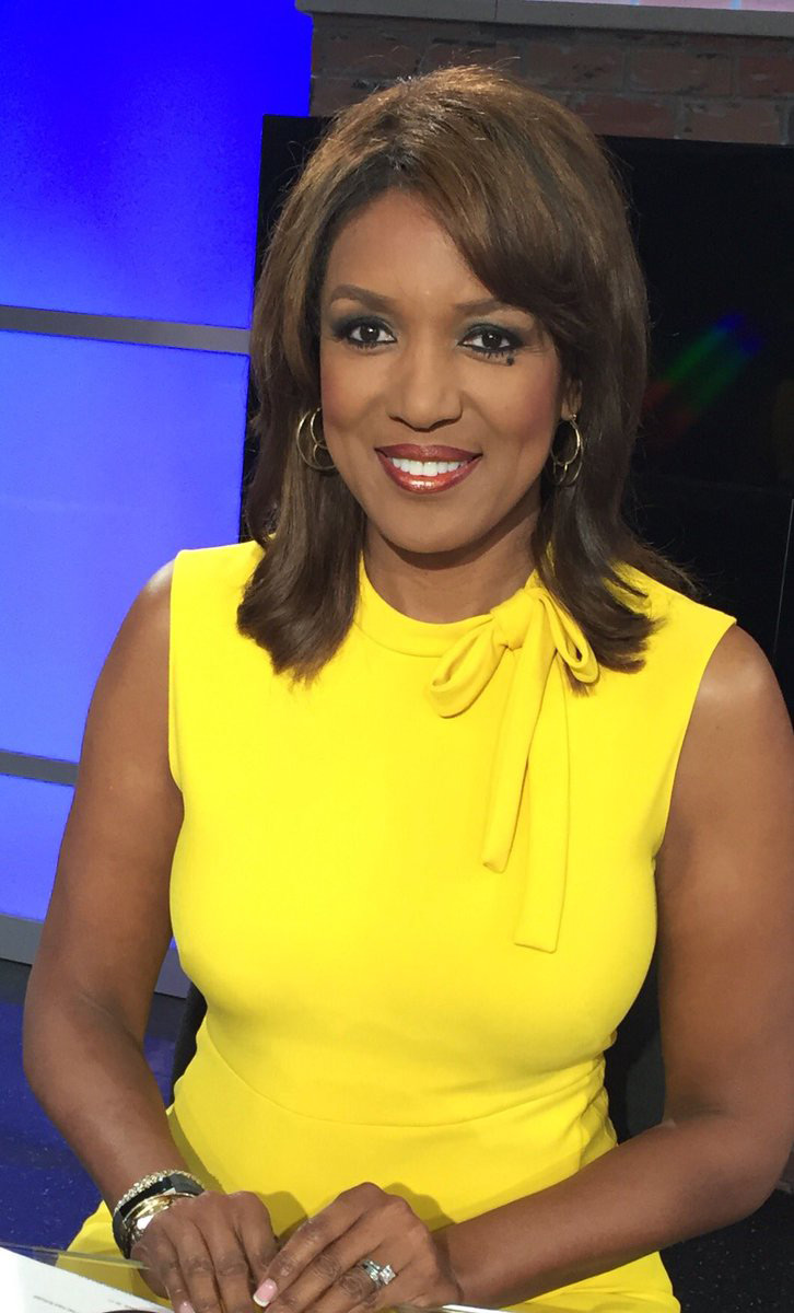 Portrait of local television news anchor Ramona Robinson in a yellow blouse with blue light coming through a window behind her.