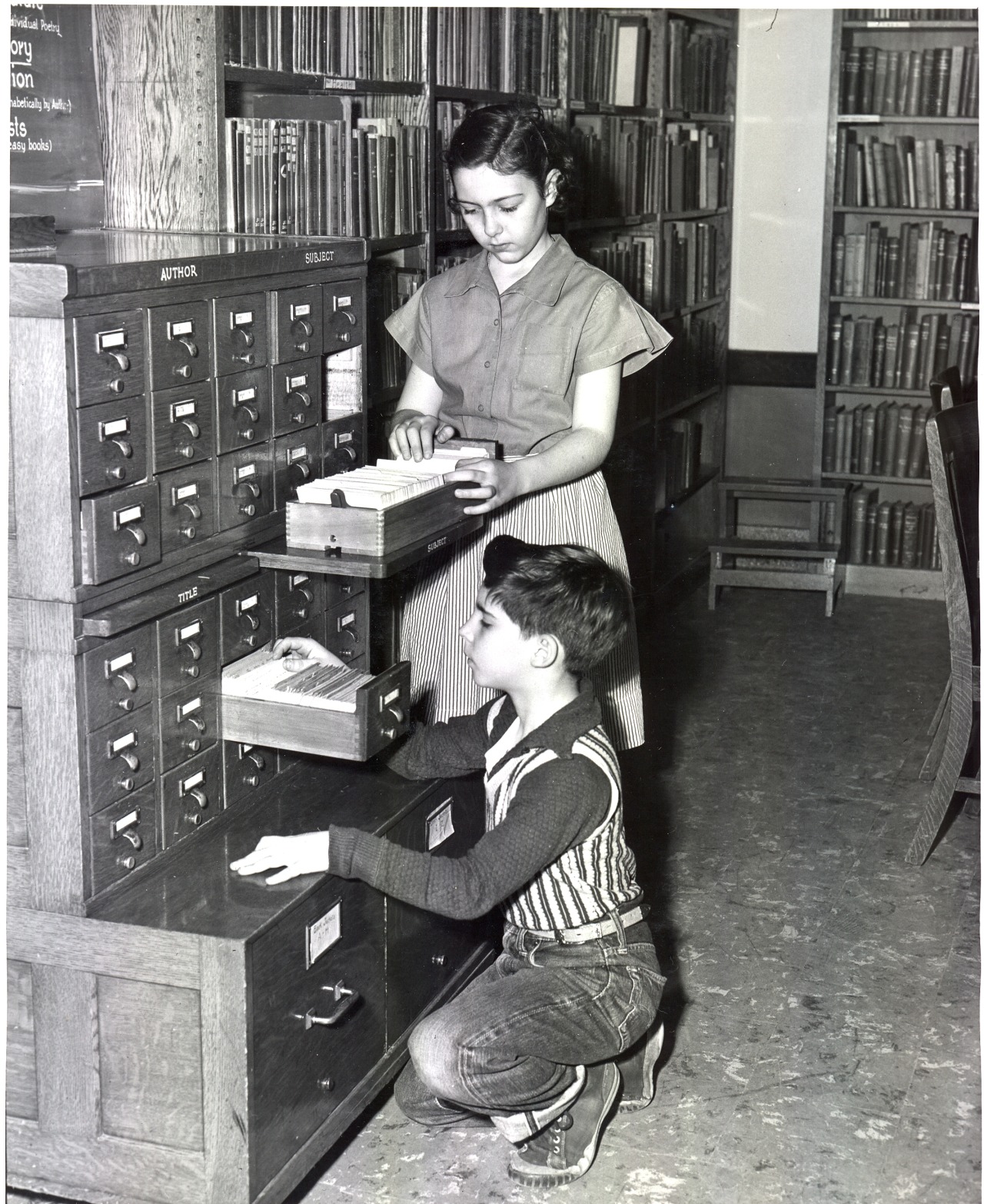 Black and white photo of a girl and boy at Hazeldell Elementary School Library, taken in 1953