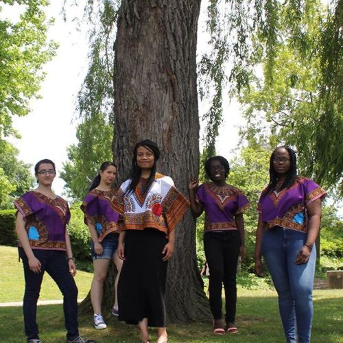 Group of African American women wearing traditional African clothing, standing by a tree