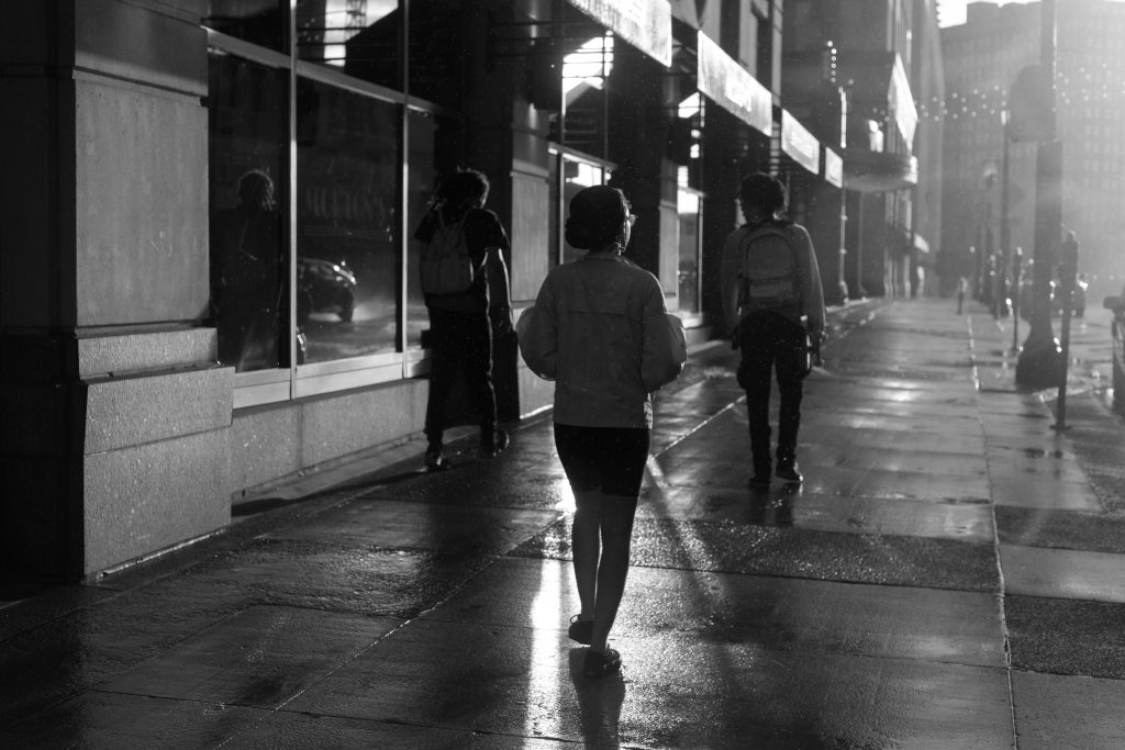 Three strangers walking down city street in the same direction