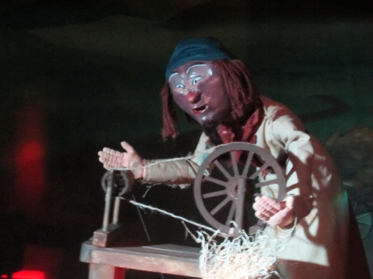 Puppet man using a spinning wheel to make silk.