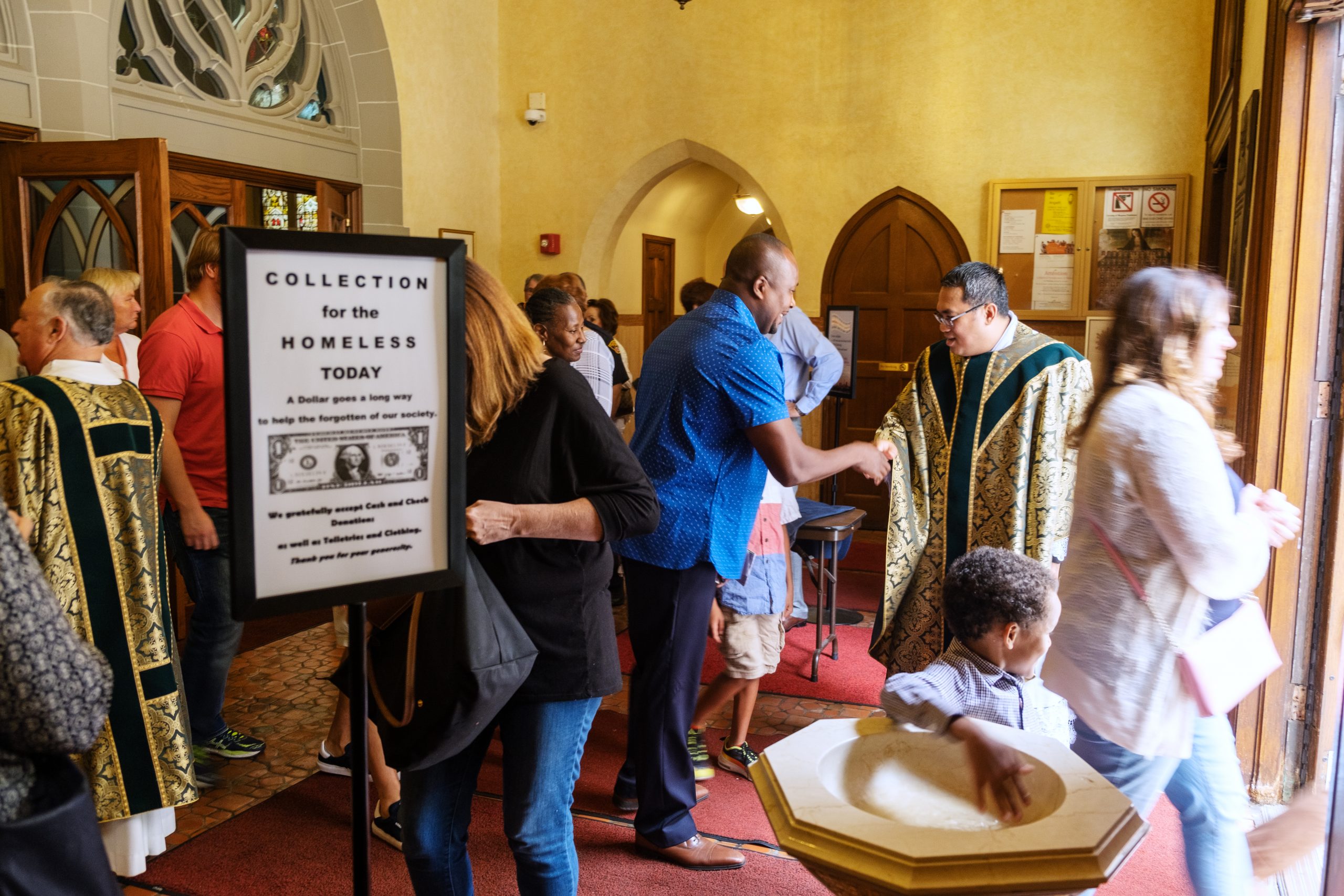 People in the entrance of a church and a sign that reads "Collection for the Homeless Today"